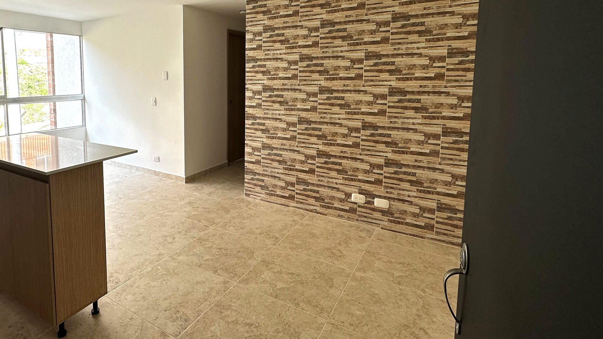 La misma cocina terminada, con isla de madera y muro revestido en piedra