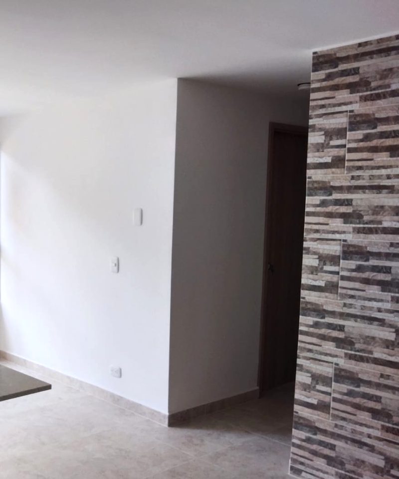 Pasillo terminado con muro revestido en piedra y puerta de madera